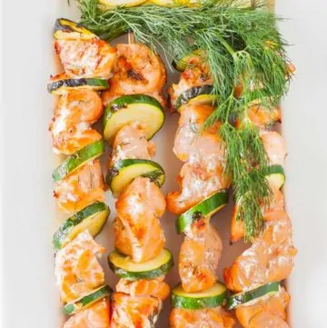 Four grilled salmon kabobs on a plate