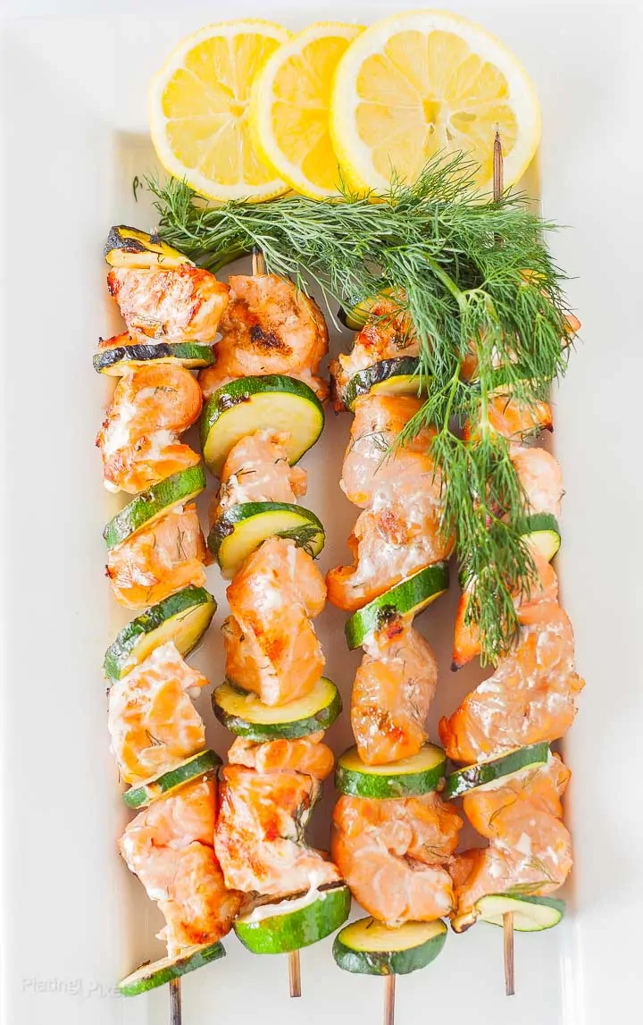 Four grilled salmon kabobs on a plate