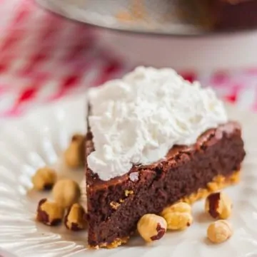 Chocolate Hazelnut Fudge Cake on a white plate with hazelnuts