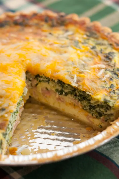 Mushroom, Spinach, and Ham Quiche in a pie pan with a slice cut out of it