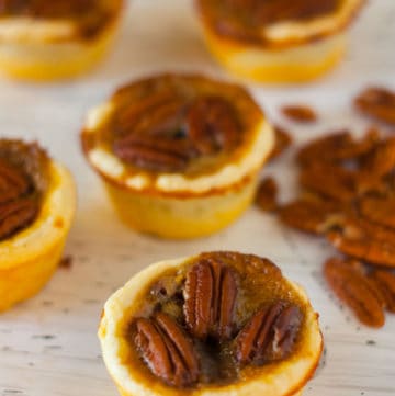 Pecan Tassies on a white table with pecans in background