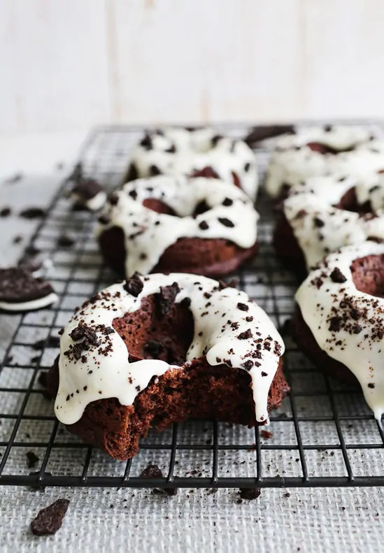 Cookies and Cream Baked Donuts on a wire rack, one with a bite taken out of it