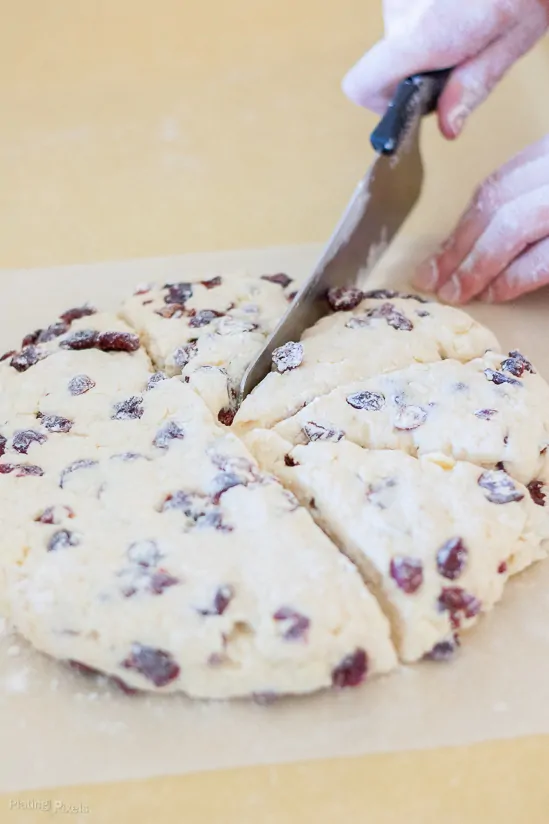 A process shot of cutting White Chocolate Cranberry Scones before being baked