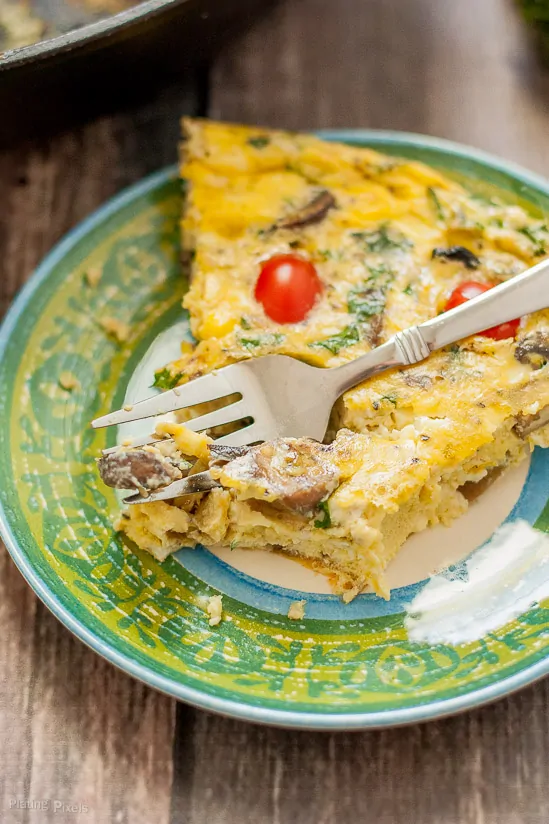 Slice of Kale and Feta Frittata on a small plate with a bit taken out of it