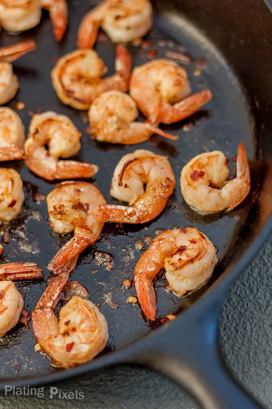 Process shot showing shrimp cooking in a pan