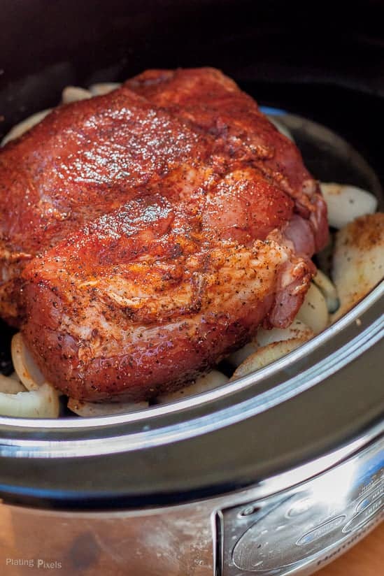 A whole piece of seasoned pork in a slow cooker ready for making pulled pork