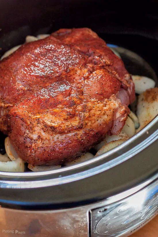 A whole piece of seasoned pork in a slow cooker ready for making pulled pork