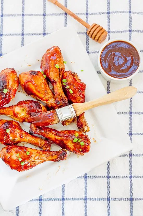 An overhead shot of Easy Honey BBQ Oven Baked Chicken Drumsticks on a plate with side dish of barbecue sauce