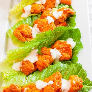 Four Buffalo Chicken Lettuce Wraps drizzled with blue cheese dressing on a white plate