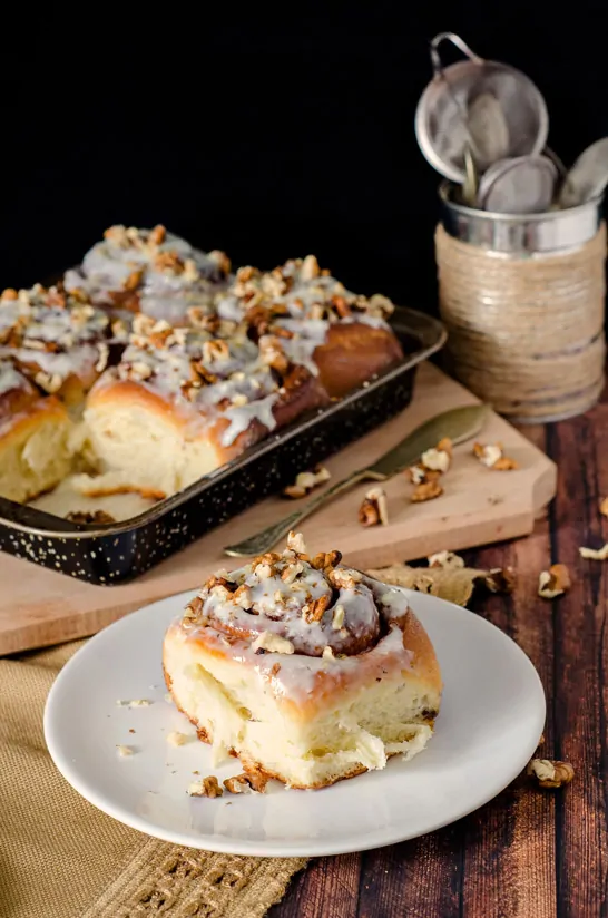 Homemade Cinnamon Roll on a plate with baking pan of more rolls in background