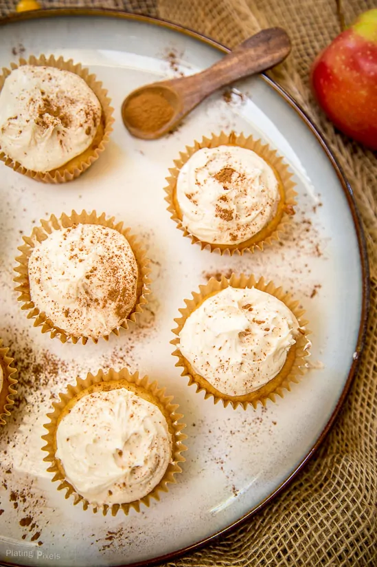 Five Spiced Apple Cider Cupcakes on a plate being topped with cinnamon garnish