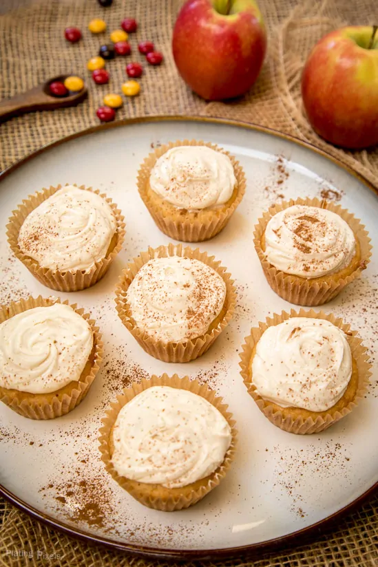 Seven Spiced Apple Cider Cupcakes on a plate with fresh apples in background
