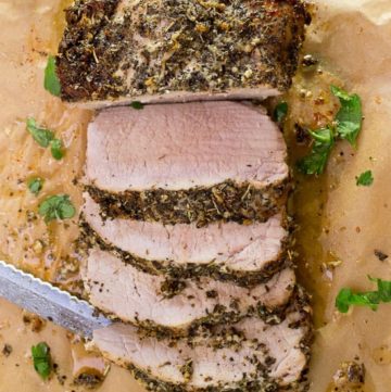 Garlic Herbed Pork Loin with Mushroom Wine Sauce on a cutting board cut into slices