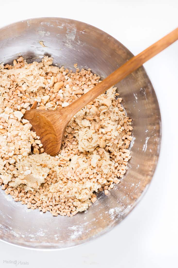 Process shot of stirring ingredients in a bowl for chewy cashew toffee cookies