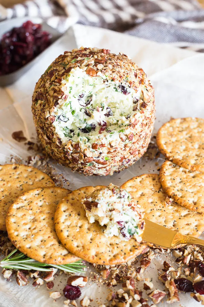 Craisins White Cheddar Cheese Ball on a plate next to crackers with some spread on it