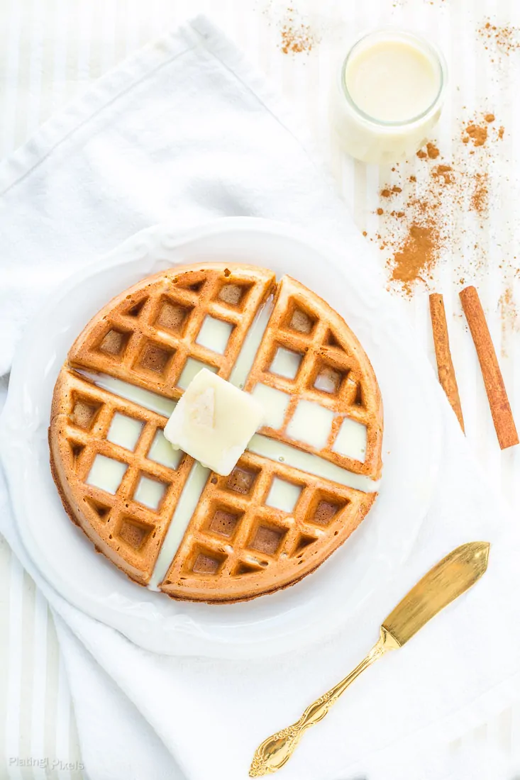 Eggnog Waffles on a plate with butter on top and cinnamon at the side