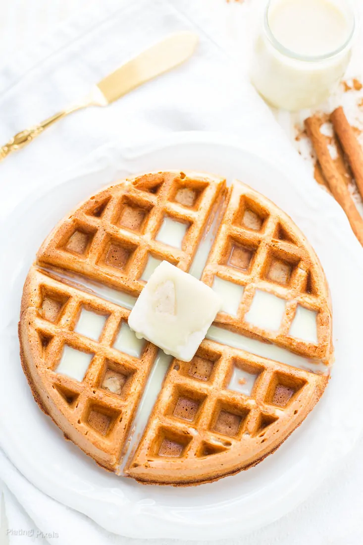 An overhead shot of Eggnog Waffles on a plate topped with butter