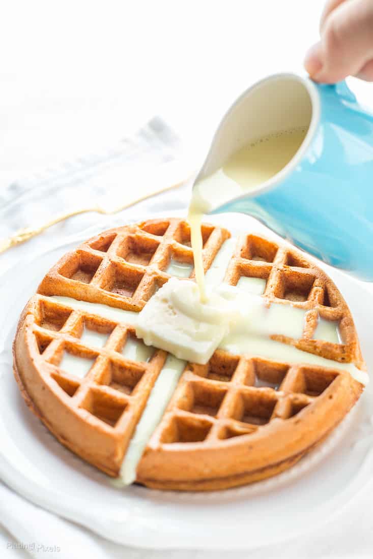 Eggnog Waffles on a plate with eggnog getting poured over the top