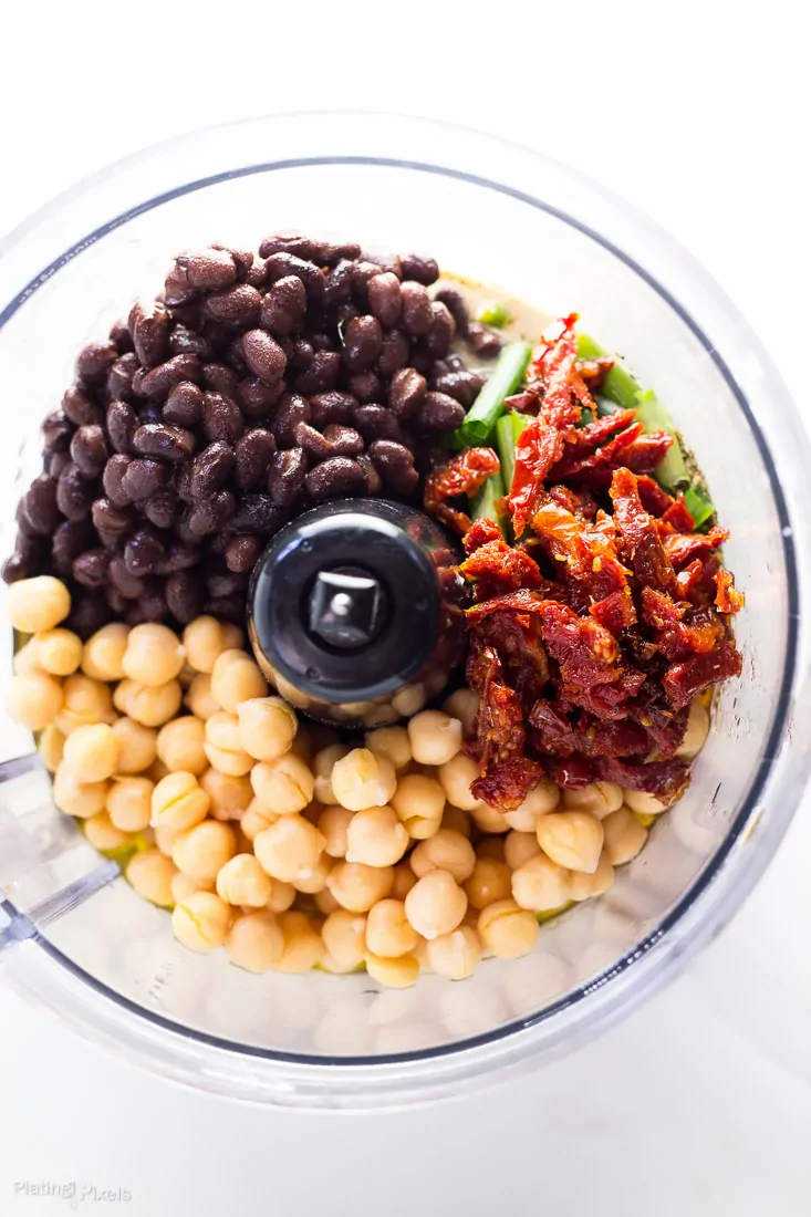 An overhead shot of ingredients to make Sun Dried Tomato Black Bean Hummus in a food processor