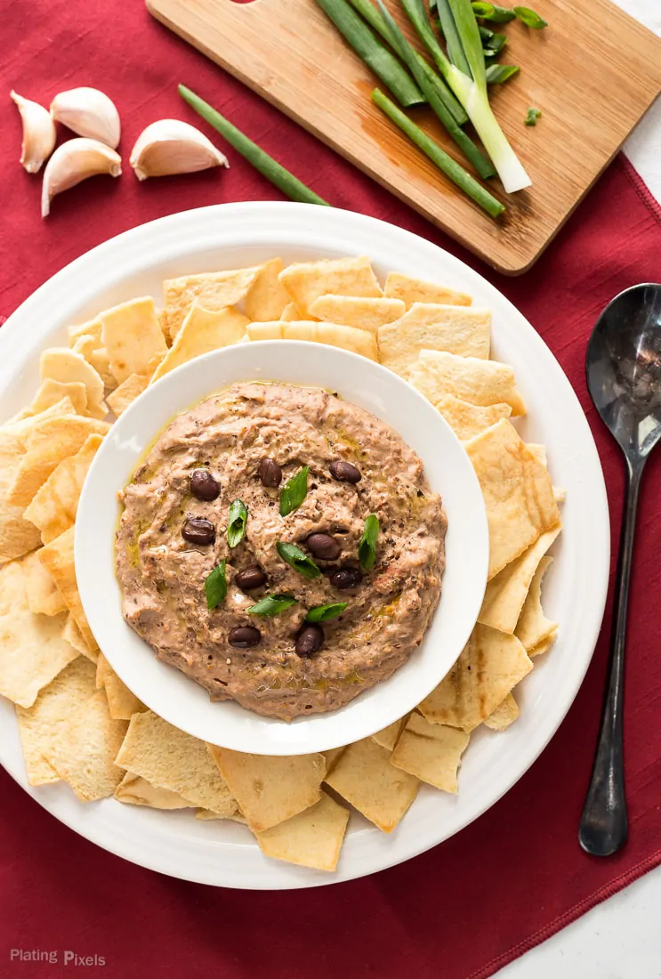 An overhead shot of Sun Dried Tomato Black Bean Hummus in a bowl with chips