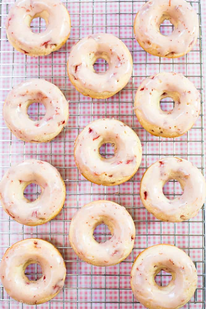 An overhead shot of Strawberry Glazed Baked Doughnuts resting on a cooling rack