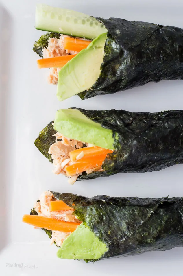 An overhead shot of three rolled Paleo Tuna Salad Wraps in nori sheets on a white plate