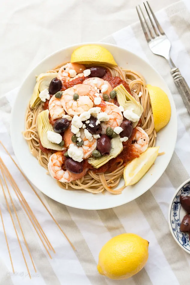 Overhead shot of a bowl of Mediterranean Shrimp Pasta with lemon wedge garnishes