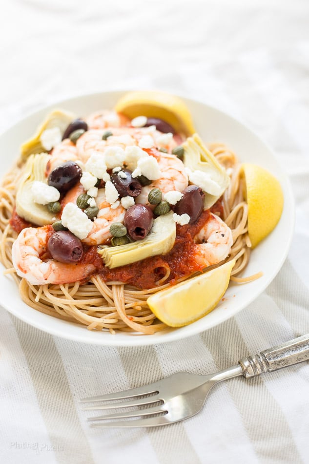 A bowl of Mediterranean Shrimp Pasta with Whole Wheat Spaghetti on a white linen