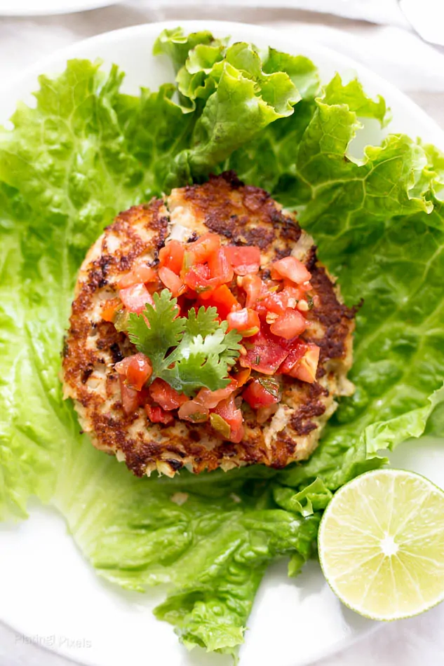 An overhead shot of a Tuna Cake on a lettuce wrap with a wedge of lime at the side