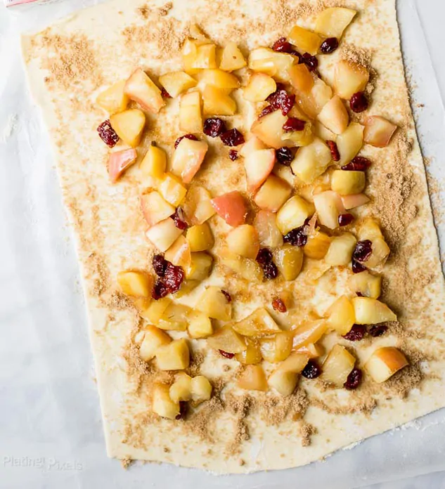Brown sugar and cooked apple pieces on a puff pastry sheet