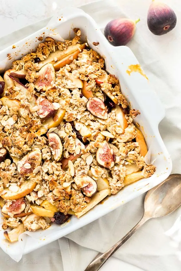 Just baked Fig, Pear and Apple Crisp in a white square baking dish with fresh figs next to it