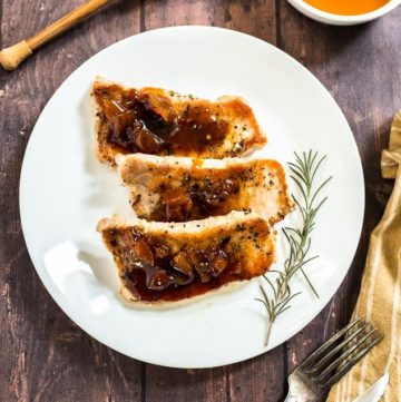 Honey Apricot Pork Chops on a white plate with rosemary
