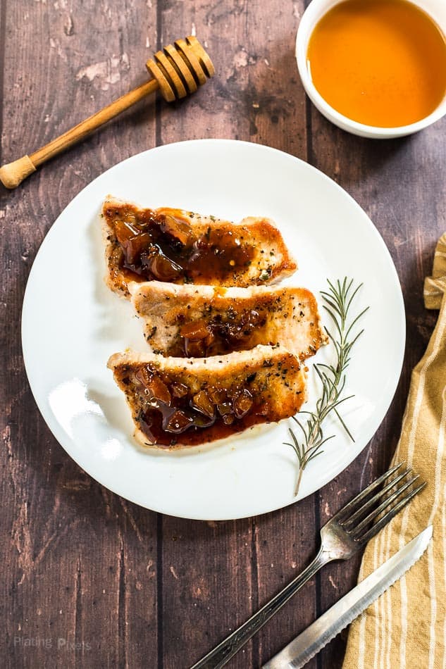 An overhead shot of Honey Apricot Pork Chops on a plate with a sprig of rosemary at the side