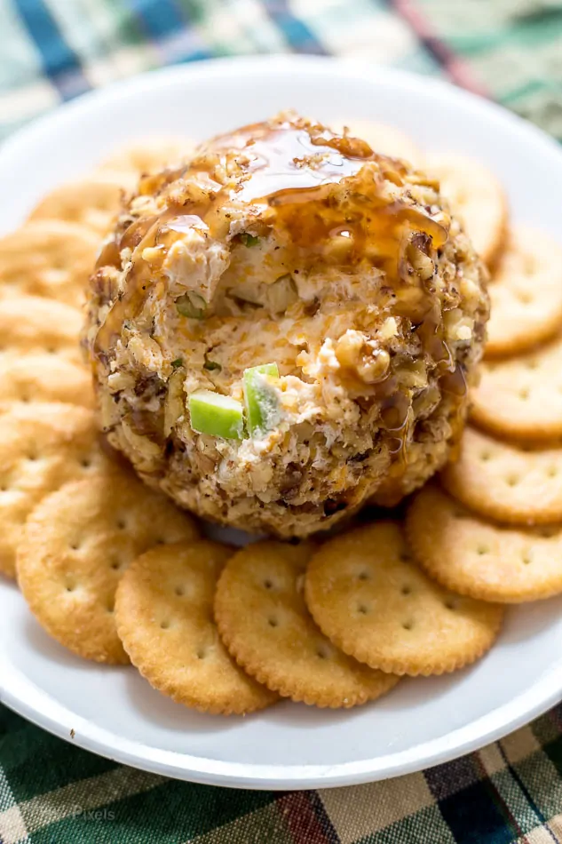 A Caramel Apple Cheese Ball on a plate surrounded by crackers