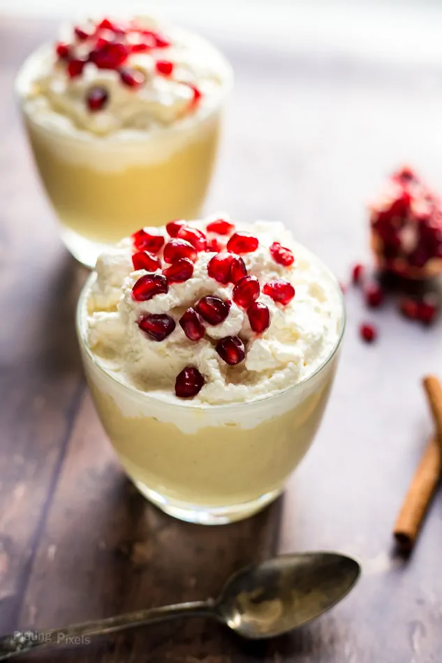A close up of Homemade Eggnog Pudding in a glass topped with pomegranate