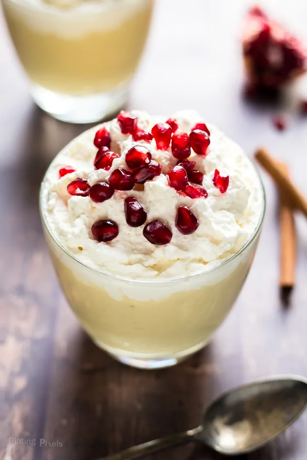 Homemade Eggnog Pudding in a glass topped with whipped cream and pomegranate