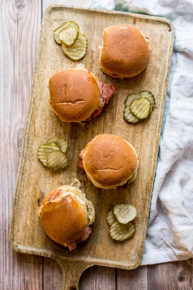 Ham and Gruyere Sliders on a wooden board with sliced pickles