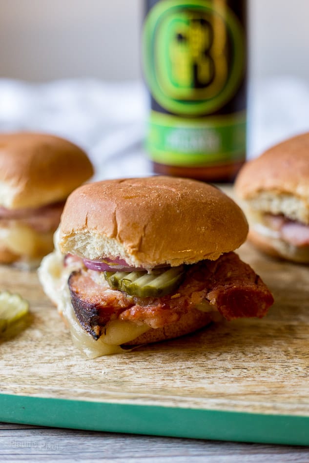 A close up of Ham and Gruyere sitting on a wooden board with beer in the background