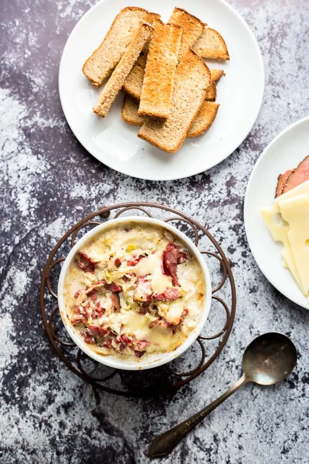 An overhead shot of a Hot Reuben Cheese Dip in a bowl with rye bread dippers at the side