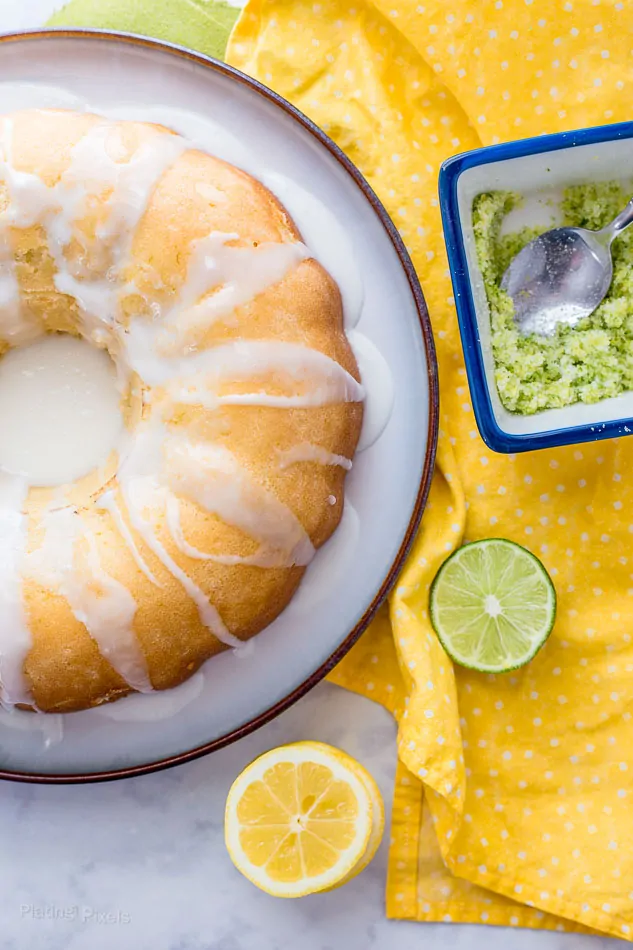 Lemon Bundt Cake drizzled with lemon glaze next to a bowl of citrus sugar crumb topping