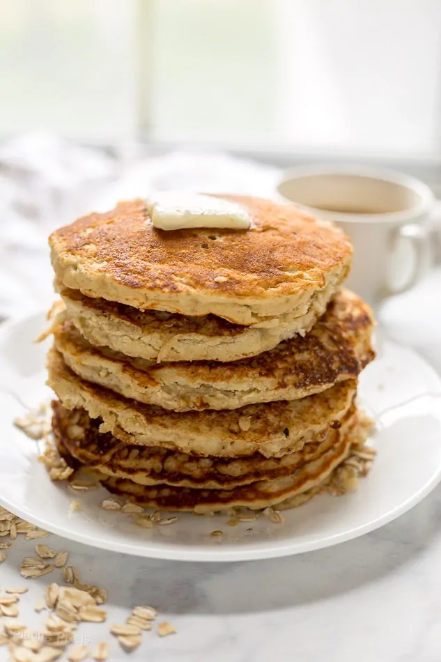 A stack of Banana Oatmeal Pancakes on a plate topped with butter