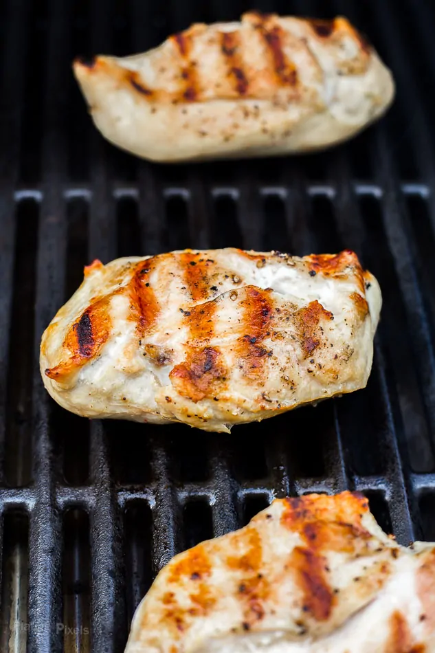 Close up of grilled chicken breast on gas grill with nice sear marks on it