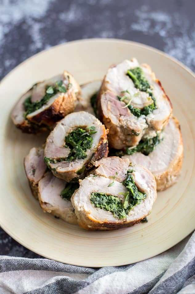 Spinach Parmesan Stuffed Pork Loin cut into slices and sitting on a serving plate