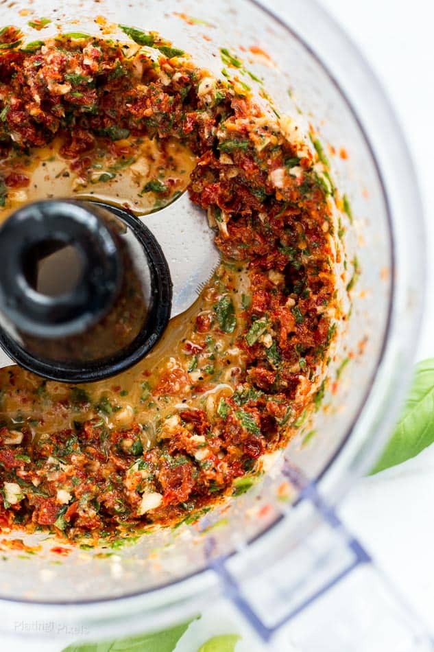 Process shot of Sun Dried Tomato, garlic and basil blended in a food processor