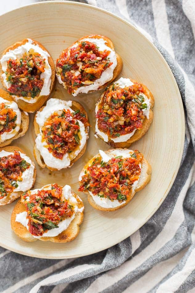 Sun Dried Tomato Ricotta Crostini on a round serving plate