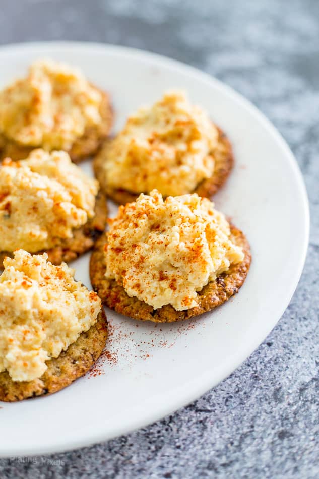 egg salad on crackers on a white plate