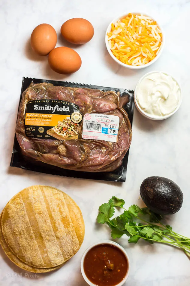 Ingredients for making Slow Cooker Carnitas Breakfast Tacos on a white marble surface