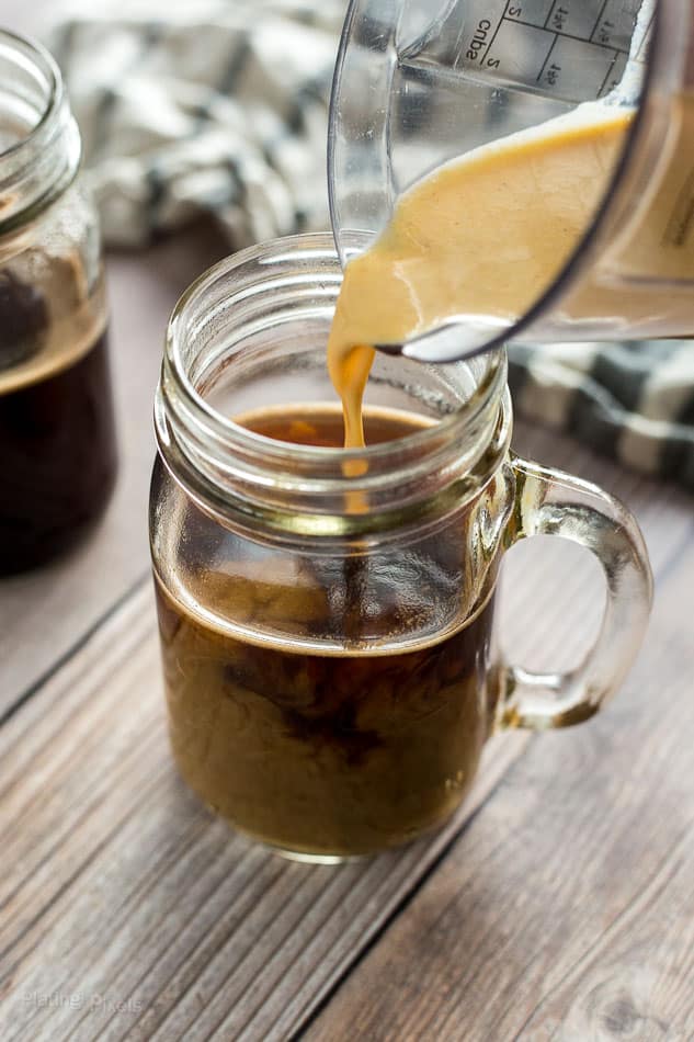 Pouring pumpkin spice cream mixture into brewed coffee in a jar