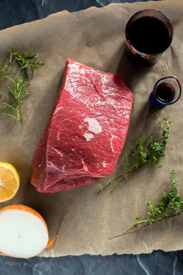 Prime rib of beef on a work surface with ingredients for marinating