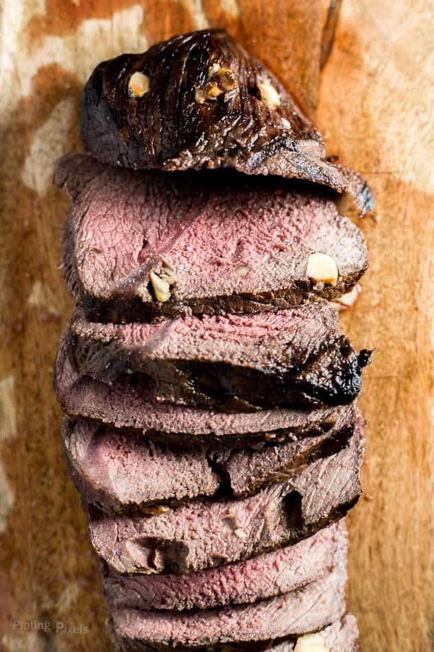 A close up of a Red Wine Marinated Prime Rib cut into slices on a cutting board
